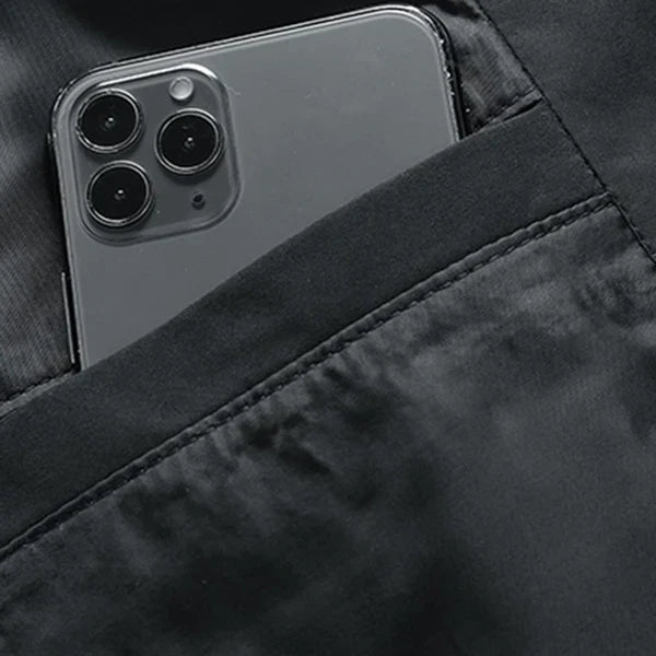 iPhone nero con tripla fotocamera in tasca giacca nera, smartphone Apple, design elegante, tecnologia avanzata, accessorio moda.