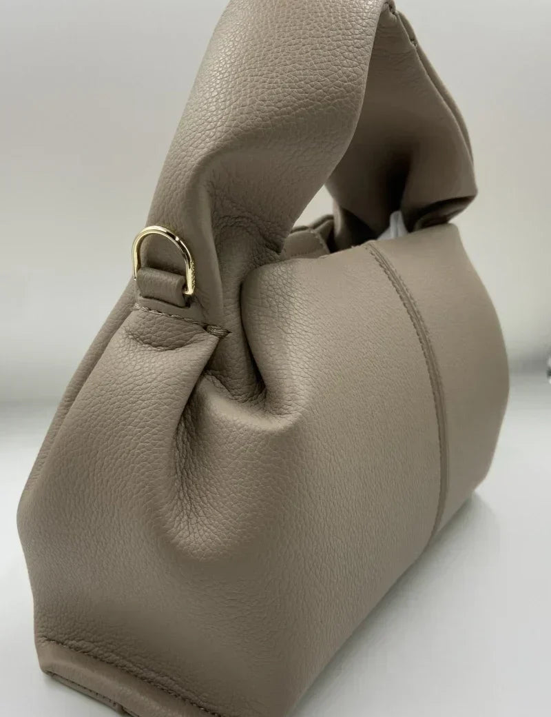 Borsa a mano in pelle beige, design elegante con manico morbido e dettagli in metallo dorato. Accessorio moda donna, stile contemporaneo.