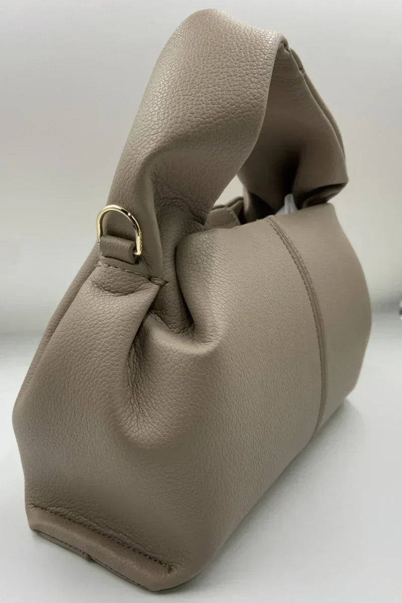 Borsa a mano in pelle beige, design elegante con manico morbido e dettagli in metallo dorato. Accessorio moda donna, stile contemporaneo.