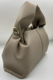 Borsa a mano in pelle beige, design elegante con manico morbido e dettagli in metallo dorato. Accessorio moda donna, stile contemporaneo.