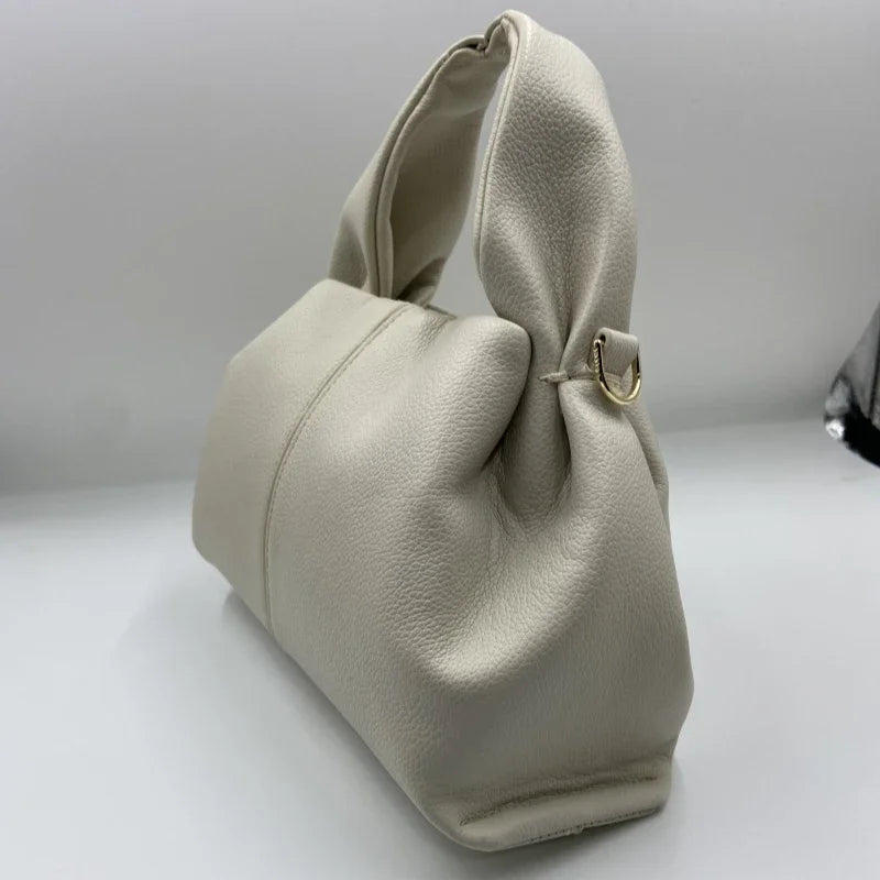 Borsa a mano in pelle bianca, design moderno e minimalista, con manico morbido e dettagli in metallo dorato. Accessorio moda elegante e versatile.