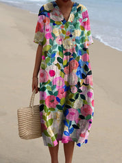 Abito estivo floreale colorato, maniche corte, scollo a V, indossato su spiaggia sabbiosa. Moda donna, abbigliamento casual, tessuto leggero.