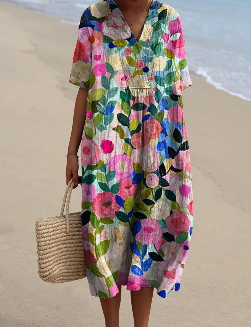 Abito estivo floreale colorato, maniche corte, scollo a V, indossato su spiaggia sabbiosa. Moda donna, abbigliamento casual, stile boho chic.
