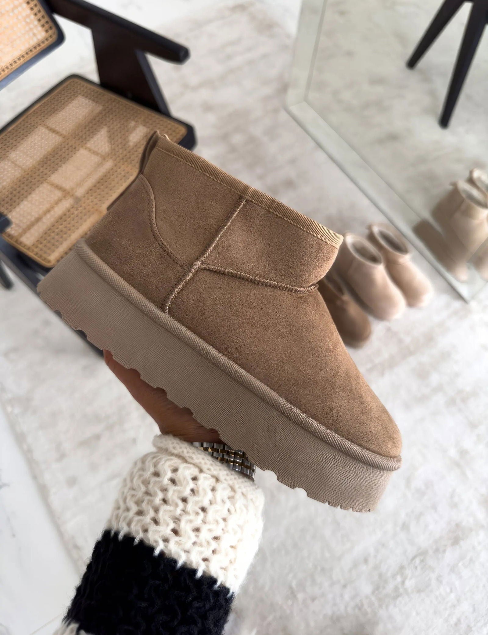 Stivaletto beige in pelle scamosciata con suola spessa, design moderno e minimalista, perfetto per l'inverno. Arredamento elegante sullo sfondo.