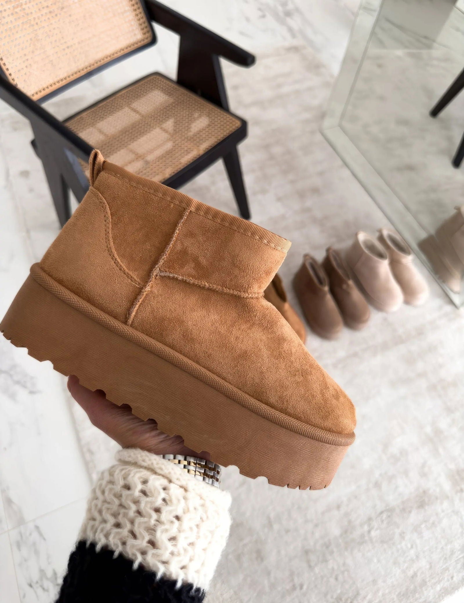 Stivaletto invernale beige in pelle scamosciata con suola spessa, tenuto in mano. Design moderno, perfetto per look casual e giornate fredde.