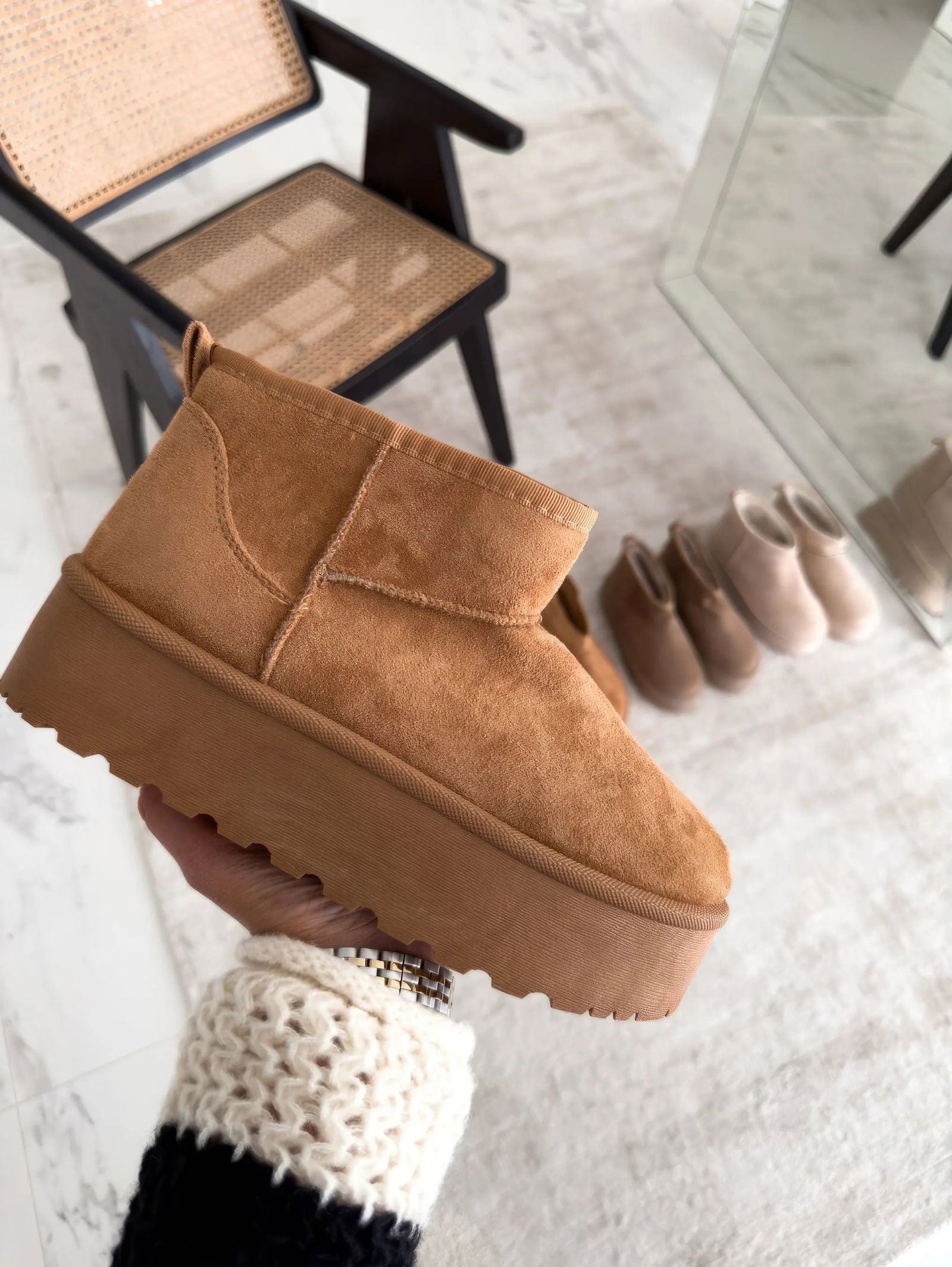 Stivaletto invernale beige in pelle scamosciata con suola spessa, tenuto in mano. Design moderno, perfetto per look casual e giornate fredde.