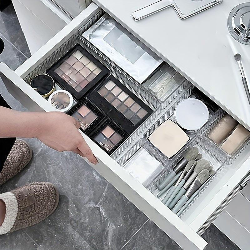 Cassetto aperto con trucchi organizzati: palette ombretti, pennelli trucco, cipria e specchio. Organizzazione cosmetici bagno moderno.