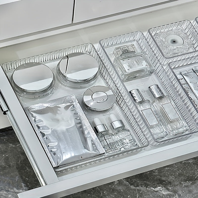 Cassetto organizzato con cosmetici: creme, sieri e profumi in contenitori trasparenti. Soluzione di stoccaggio elegante per prodotti di bellezza.