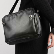 Borsa a tracolla in pelle nera elegante, design minimalista, chiusura con zip, ideale per moda donna, accessorio versatile e moderno.