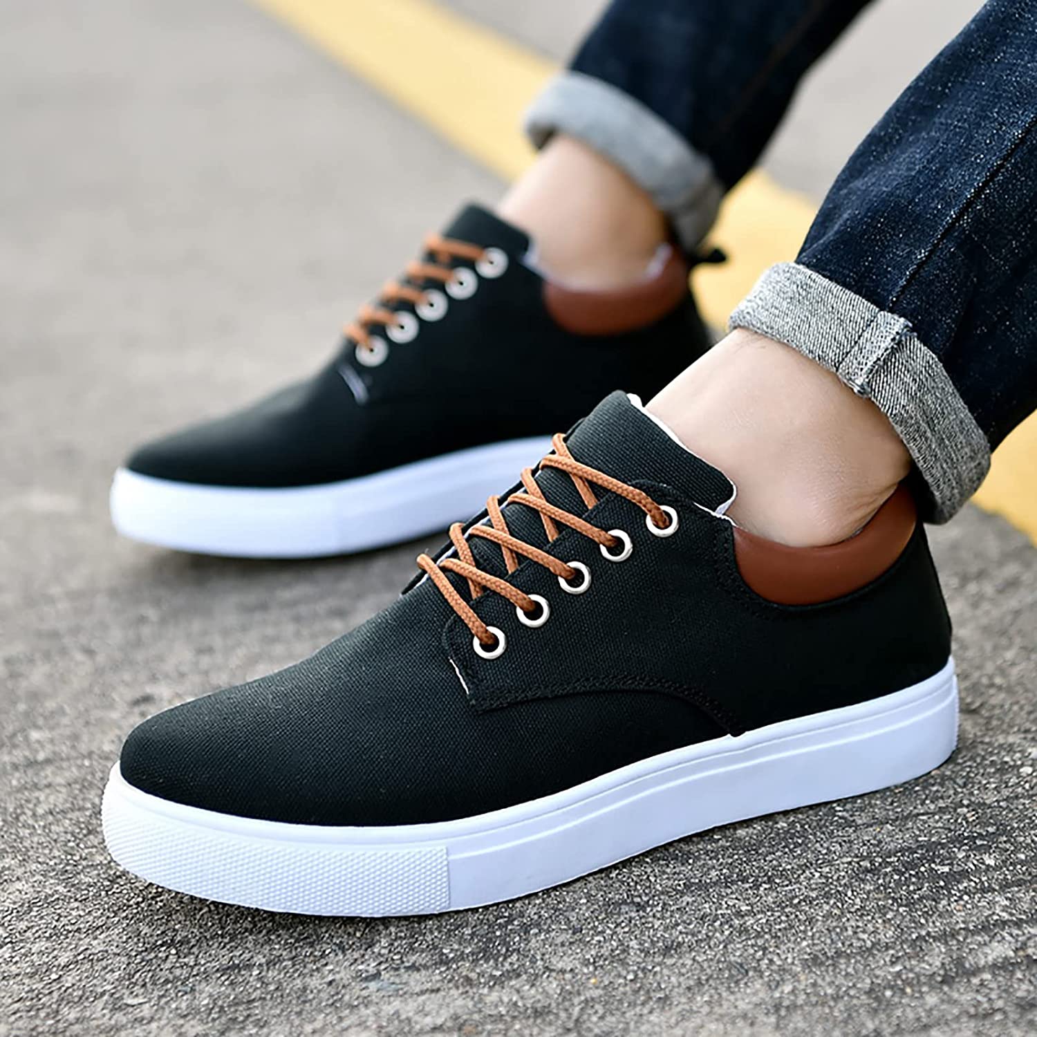Scarpe da ginnastica nere da uomo con suola bianca, lacci marroni, indossate con jeans. Scarpe casual eleganti per passeggiate e tempo libero.