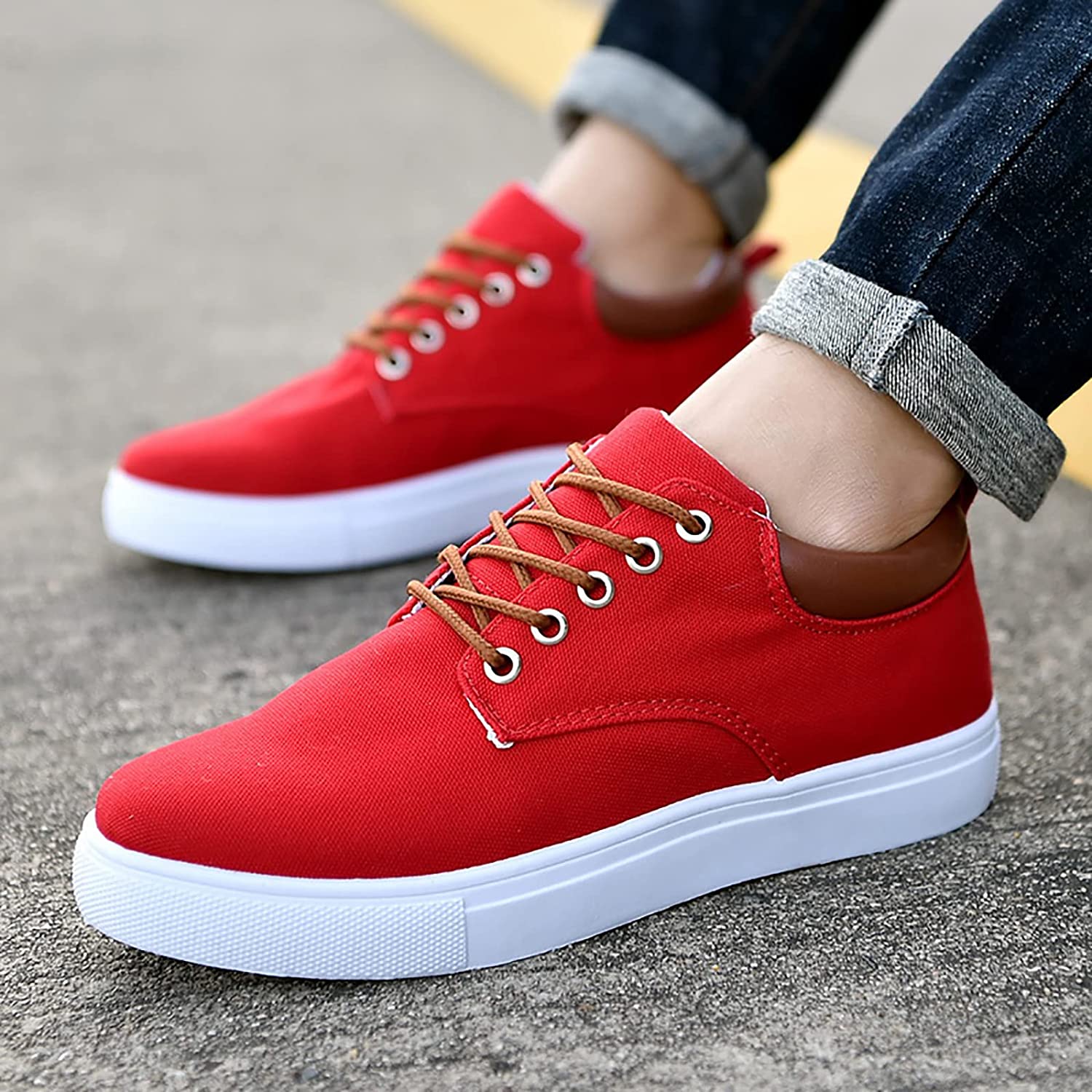 Scarpe da ginnastica rosse da uomo, suola bianca, lacci marroni, indossate su strada asfaltata. Design casual, moda urbana, comfort quotidiano.