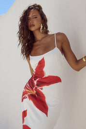 Abito estivo bianco con stampa floreale rossa, spalline sottili, indossato da modella con capelli mossi. Moda donna, abbigliamento estivo elegante.
