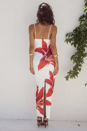 Abito lungo estivo bianco con stampa floreale rossa, spalline sottili, schiena scoperta, indossato da donna. Elegante e alla moda per eventi estivi.