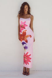 Abito lungo estivo rosa con stampa floreale vivace, spalline sottili, indossato da modella su sfondo bianco. Moda donna, abbigliamento elegante.