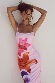 Donna con abito estivo rosa a fiori, spalline sottili, sfondo bianco. Moda femminile, abbigliamento estivo elegante, stile floreale.