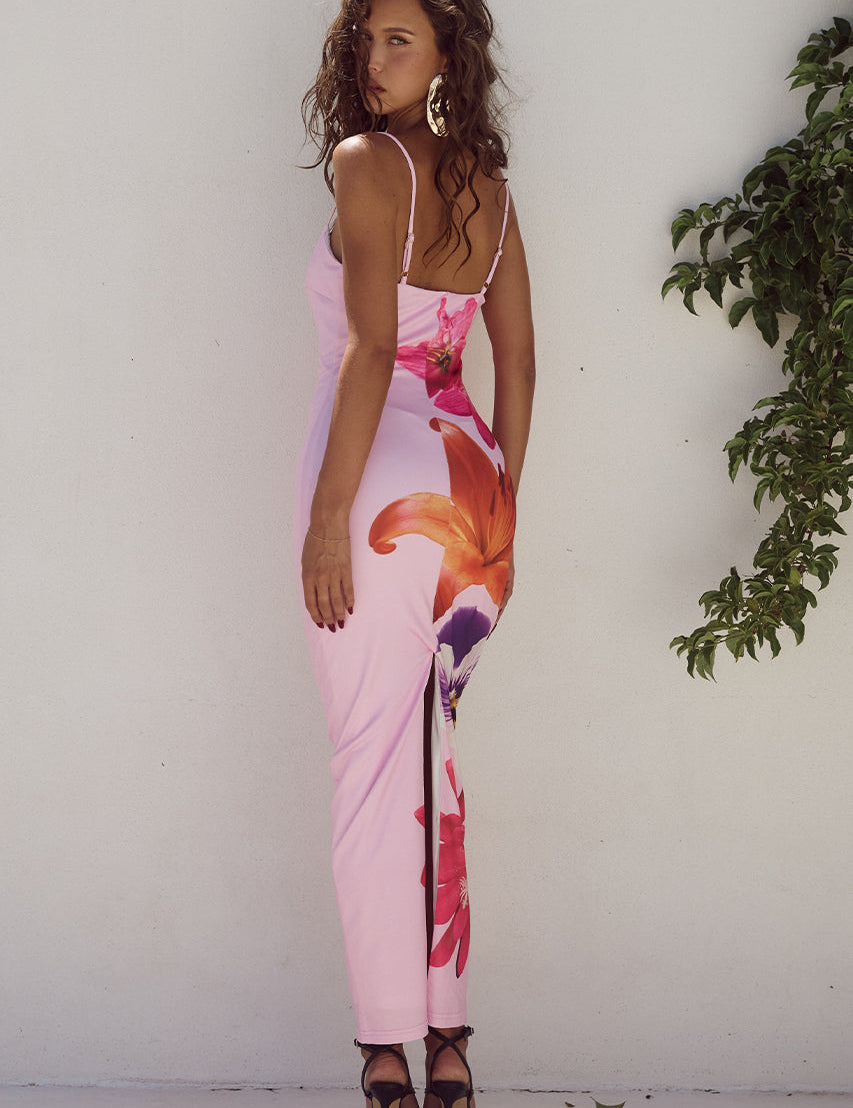 Abito lungo rosa con stampa floreale, donna di spalle, sandali neri, sfondo bianco, moda estiva elegante, abbigliamento femminile trendy.