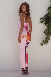 Abito lungo rosa con stampa floreale, donna di spalle, sandali neri, sfondo bianco, moda estiva elegante, abbigliamento femminile trendy.