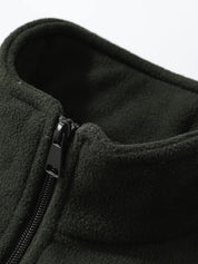Giacca in pile verde scuro con cerniera nera, collo alto. Tessuto caldo e morbido, ideale per l'inverno. Abbigliamento outdoor uomo.