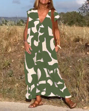 Abito lungo estivo verde e bianco con motivo astratto, indossato da donna all'aperto. Perfetto per moda casual, stile boho chic.