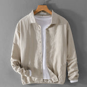 Giacca beige in lino su gruccia, stile casual, con camicia bianca sotto. Moda uomo, abbigliamento primaverile, tessuto leggero e traspirante.