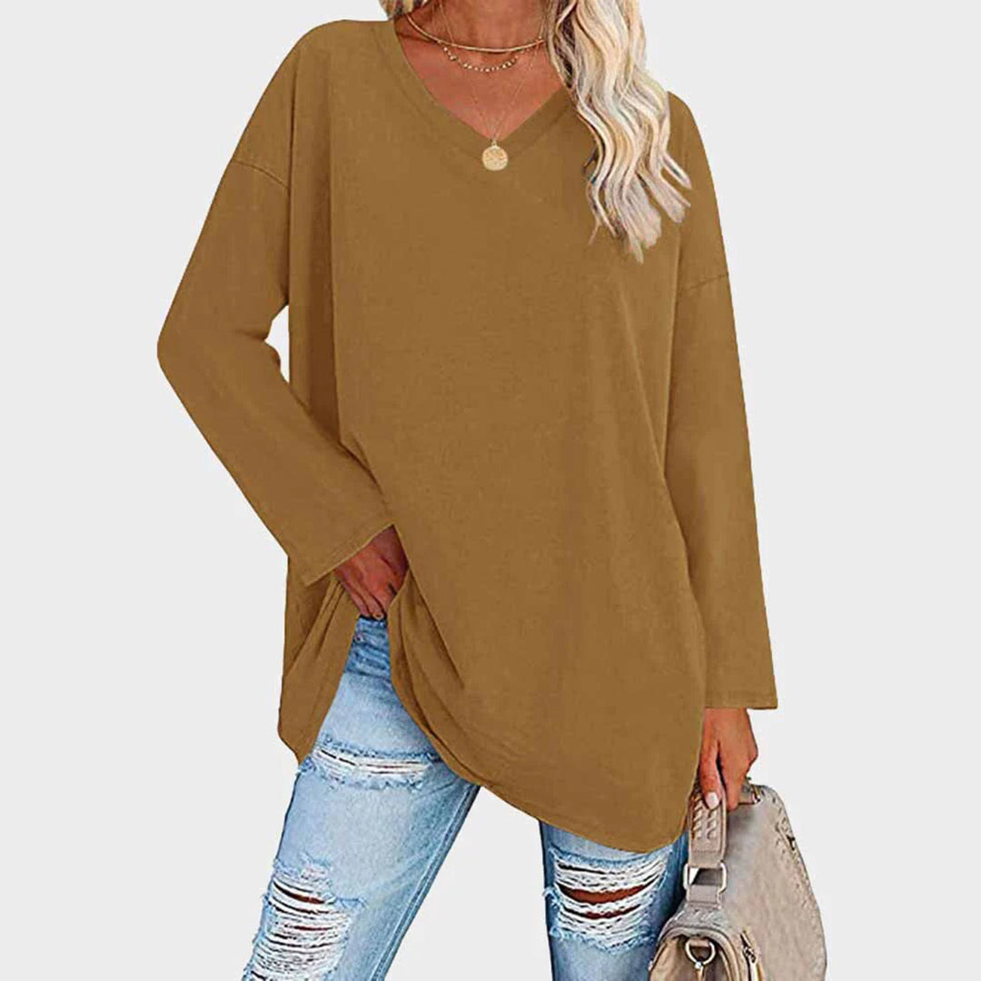 Maglia oversize marrone da donna con scollo a V, abbinata a jeans strappati e borsa beige. Look casual e alla moda per l'autunno.