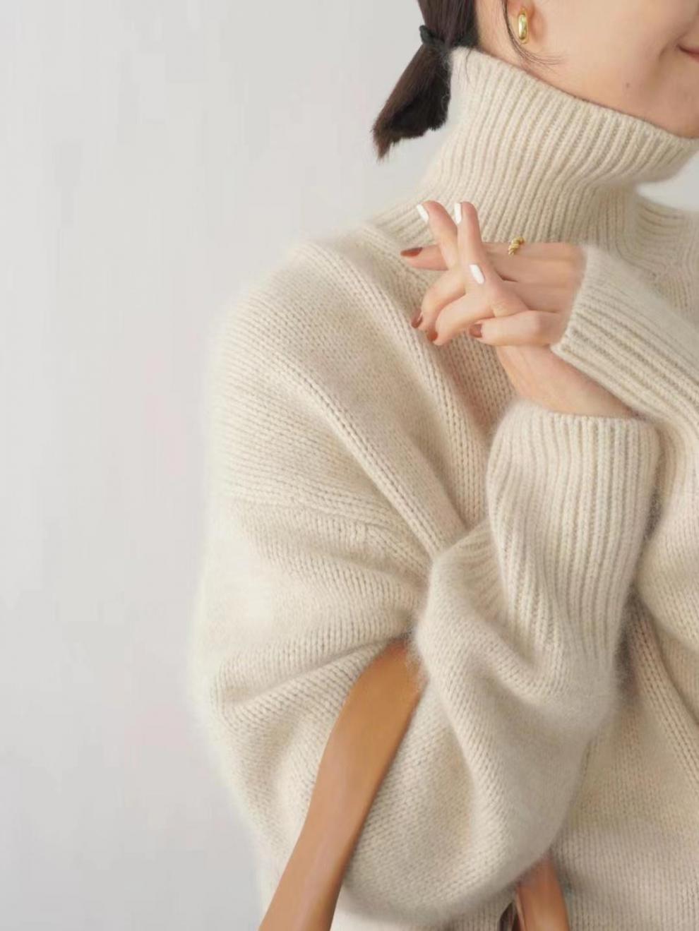 Donna con maglione a collo alto in lana beige, orecchini dorati e borsa in pelle marrone. Stile autunnale elegante e caldo.