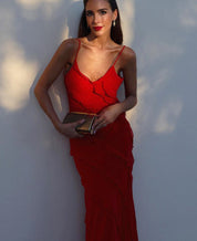Donna in abito rosso elegante, lungo e aderente, con borsa a mano dorata. Look da sera sofisticato, moda femminile, abbigliamento formale.
