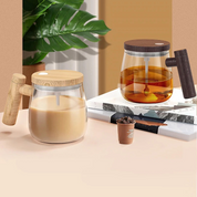 Due caraffe in vetro con coperchi in legno, una con caffè e una con latte, su un tavolo con libri e pianta decorativa. Design moderno e minimalista.