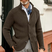 Giacca cardigan marrone da uomo in maglia, abbinata a camicia bianca e foulard blu, stile casual elegante, perfetta per l'autunno.
