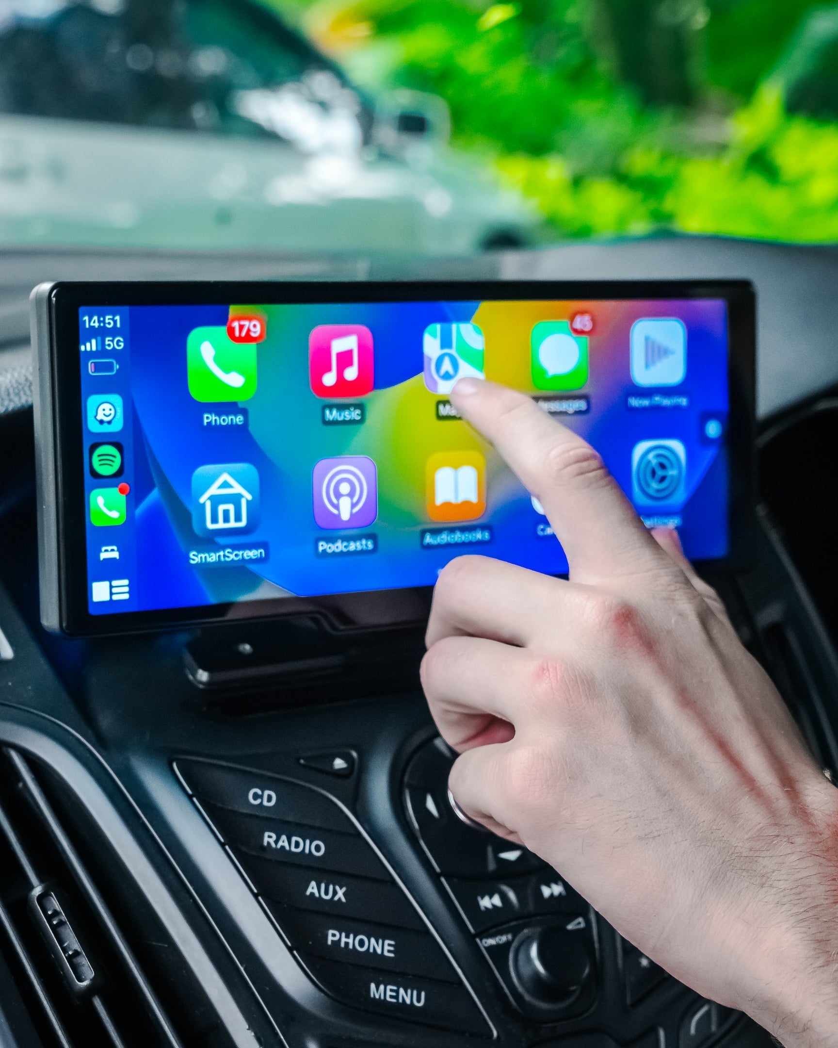 Mano che interagisce con schermo touchscreen auto, display multimediale con app di navigazione, musica e comunicazione, tecnologia avanzata auto.