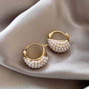 Orecchini a cerchio dorati con perle su tessuto beige, eleganti e raffinati, ideali per moda donna, accessori gioielli di lusso.