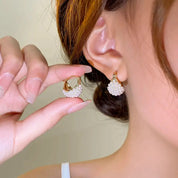 Orecchini a cerchio dorati con perle bianche indossati da una donna. Gioielli eleganti, moda femminile, accessori di lusso.