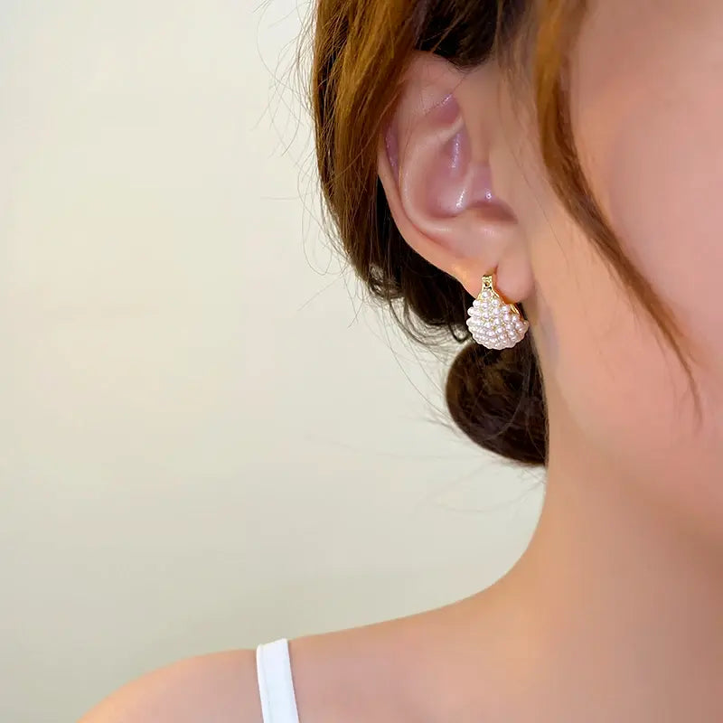 Orecchino a forma di ventaglio con perle bianche su lobo femminile, elegante accessorio moda, gioielli donna, stile raffinato, dettaglio orecchio.