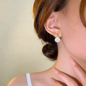 Orecchino pendente donna con perle bianche, design elegante, indossato su lobo, moda gioielli, accessorio chic, stile raffinato.