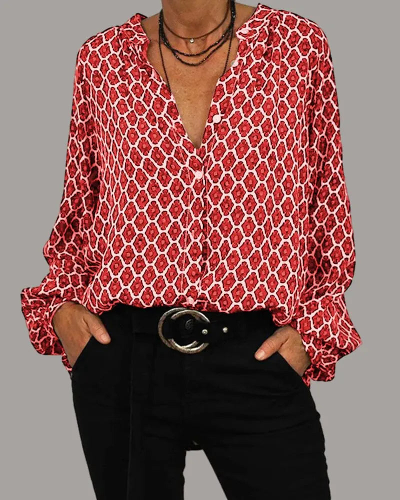 Camicia donna rossa a fantasia geometrica, maniche lunghe, scollo a V, abbinata a pantaloni neri e cintura con fibbia rotonda.