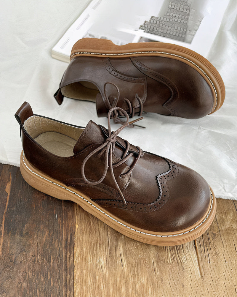 Scarpe stringate in pelle marrone su sfondo di legno, design classico con suola in gomma chiara. Eleganti e versatili per uomo e donna.