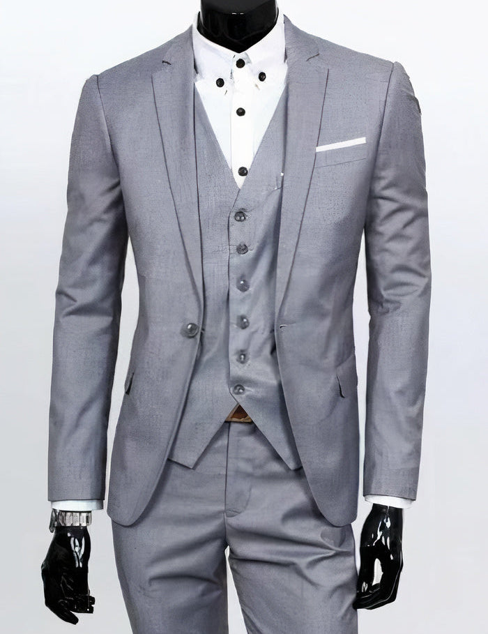Abito elegante da uomo grigio chiaro, tre pezzi, con giacca, gilet e pantaloni coordinati, camicia bianca a bottoni, ideale per cerimonie e matrimoni.