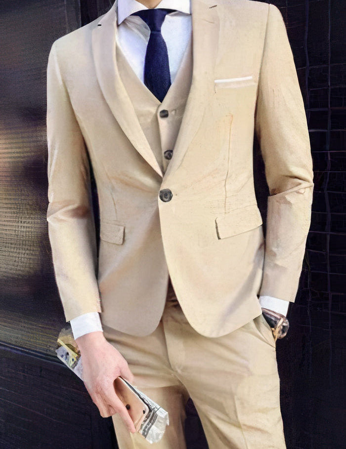 Abito elegante uomo beige, tre pezzi, cravatta blu, camicia bianca, orologio da polso, smartphone in mano. Moda formale maschile.