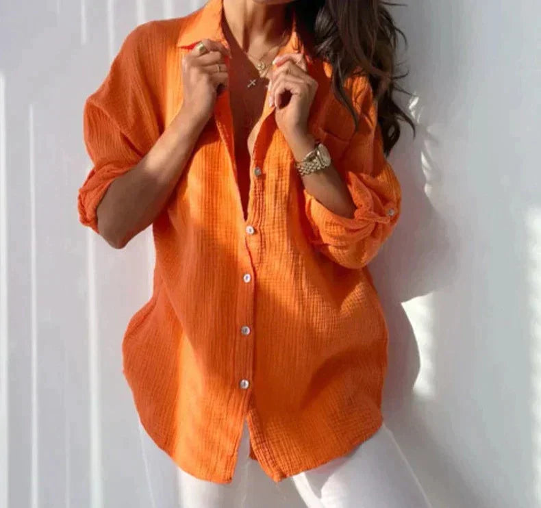 Camicia donna arancione in cotone, maniche lunghe, abbinata a pantaloni bianchi. Moda casual estiva, stile elegante e confortevole.