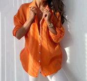 Camicia donna arancione in cotone, maniche lunghe, abbinata a pantaloni bianchi. Moda casual estiva, stile elegante e confortevole.