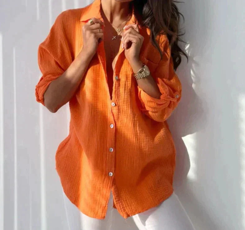 Camicia donna arancione in cotone, maniche lunghe, abbinata a pantaloni bianchi. Moda casual estiva, stile elegante e confortevole.