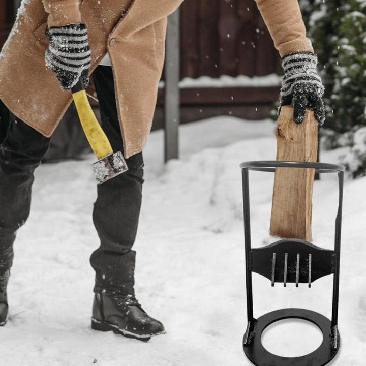 Uomo spacca legna con ascia gialla in giardino innevato, indossa cappotto beige e guanti a righe. Spaccalegna nero in primo piano.