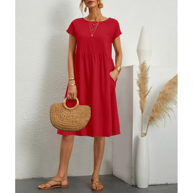 Donna con abito rosso estivo, borsa di paglia e sandali. Moda casual elegante, accessori dorati, sfondo bianco minimalista.