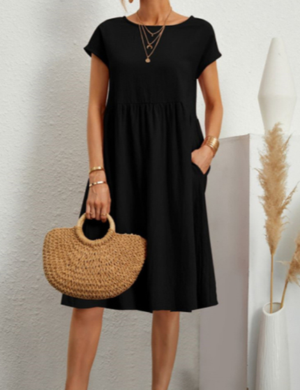 Abito nero estivo donna, maniche corte, lunghezza al ginocchio, con borsa paglia intrecciata. Look casual elegante, moda femminile 2023.