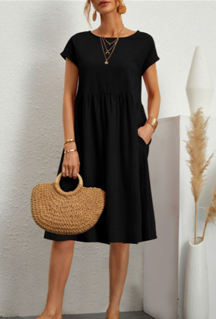 Abito nero estivo donna, maniche corte, lunghezza al ginocchio, con borsa paglia intrecciata. Look casual elegante, moda femminile 2023.