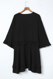 Abito nero donna con volant, maniche ampie, lunghezza media, su appendiabiti. Elegante e versatile, ideale per occasioni formali e casual.