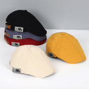 Cappelli piatti in cotone multicolore, stile vintage, con etichetta, disponibili in nero, rosso, grigio, giallo e beige. Accessori moda uomo.