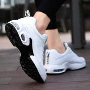 Scarpe da ginnastica bianche da donna con suola ammortizzata nera, design moderno e traspirante, ideali per corsa e fitness.
