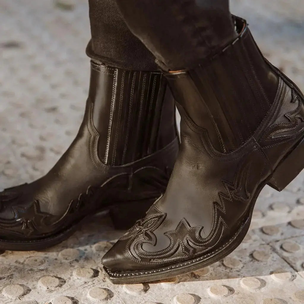Stivali texani neri in pelle con dettagli ricamati, punta affusolata e tacco basso. Scarpe western eleganti per uomo, moda autunno-inverno.