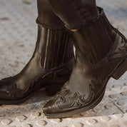 Stivali texani neri in pelle con dettagli ricamati, punta affusolata e tacco basso. Scarpe western eleganti per uomo, moda autunno-inverno.